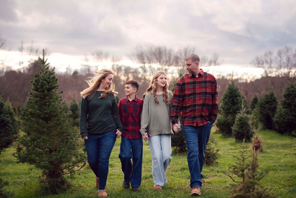 Family in plaid walking among Christmas trees at a holiday mini session