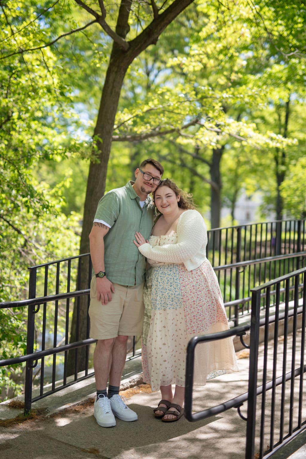 Engaged couple embracing on a sunlit garden staircase